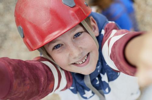 Boy in red helmet looking up through climbing frame