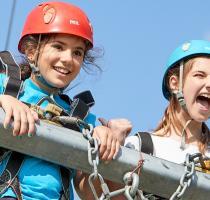 Two girls in helmets and harnesses on giant swing