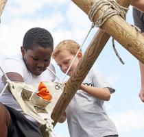 children building a large wooden ballista with poles and ropes